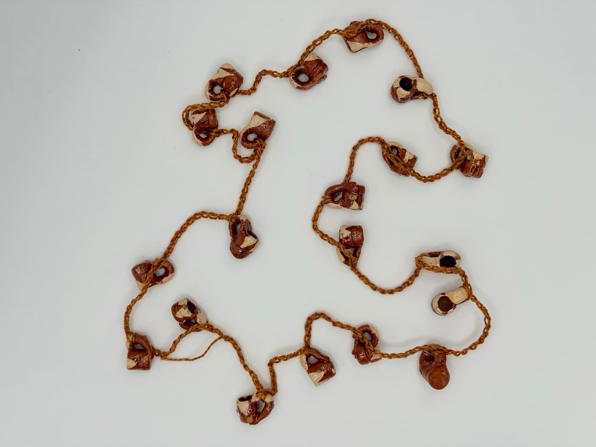 Canela y Barro, a 28-inch collar of cinnamon-red and cream jarritos laid flat on a white background.