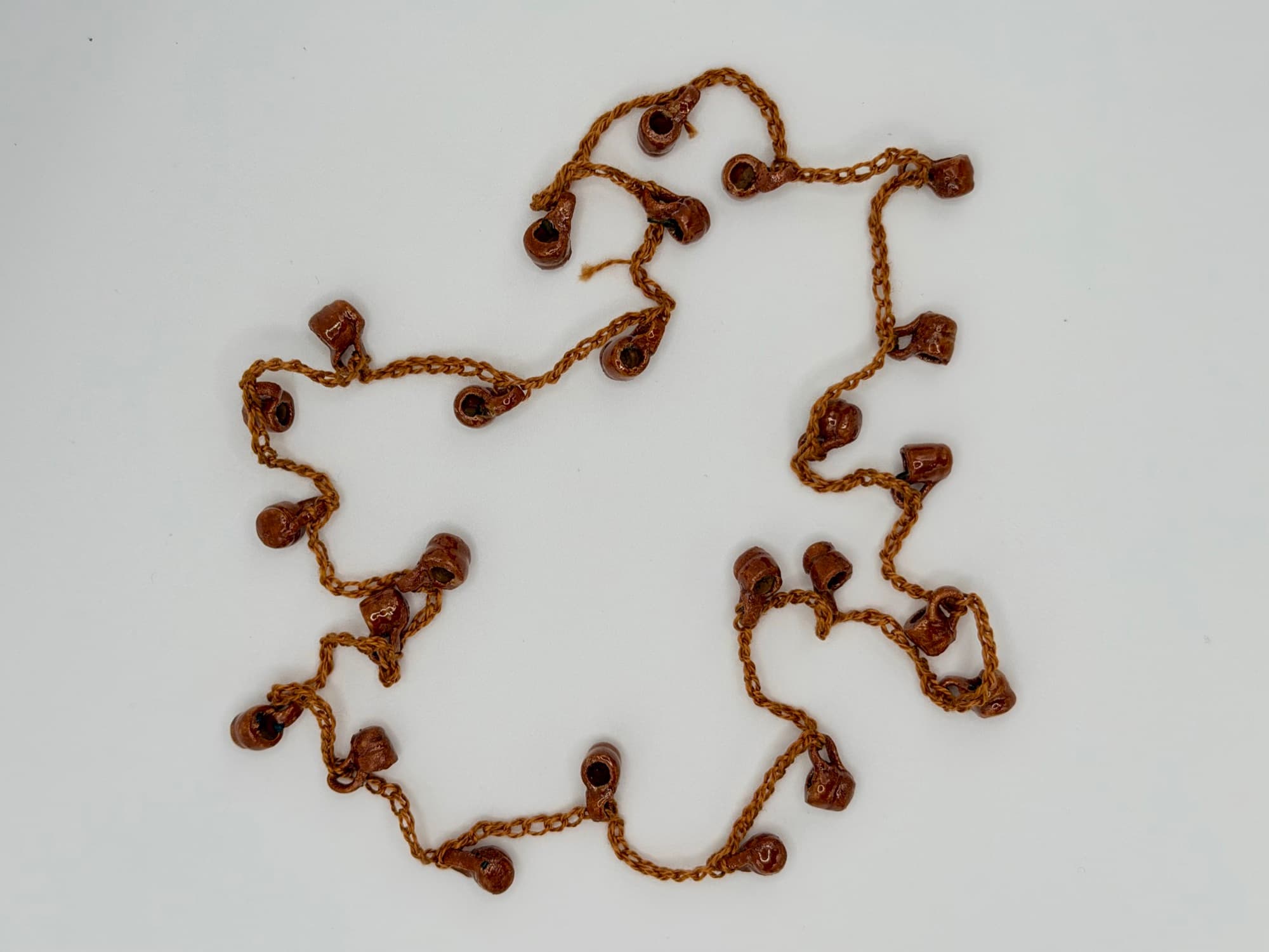 Fiesta de Barro, a 26-inch collar of glossy natural clay jarritos laid flat on a white background.