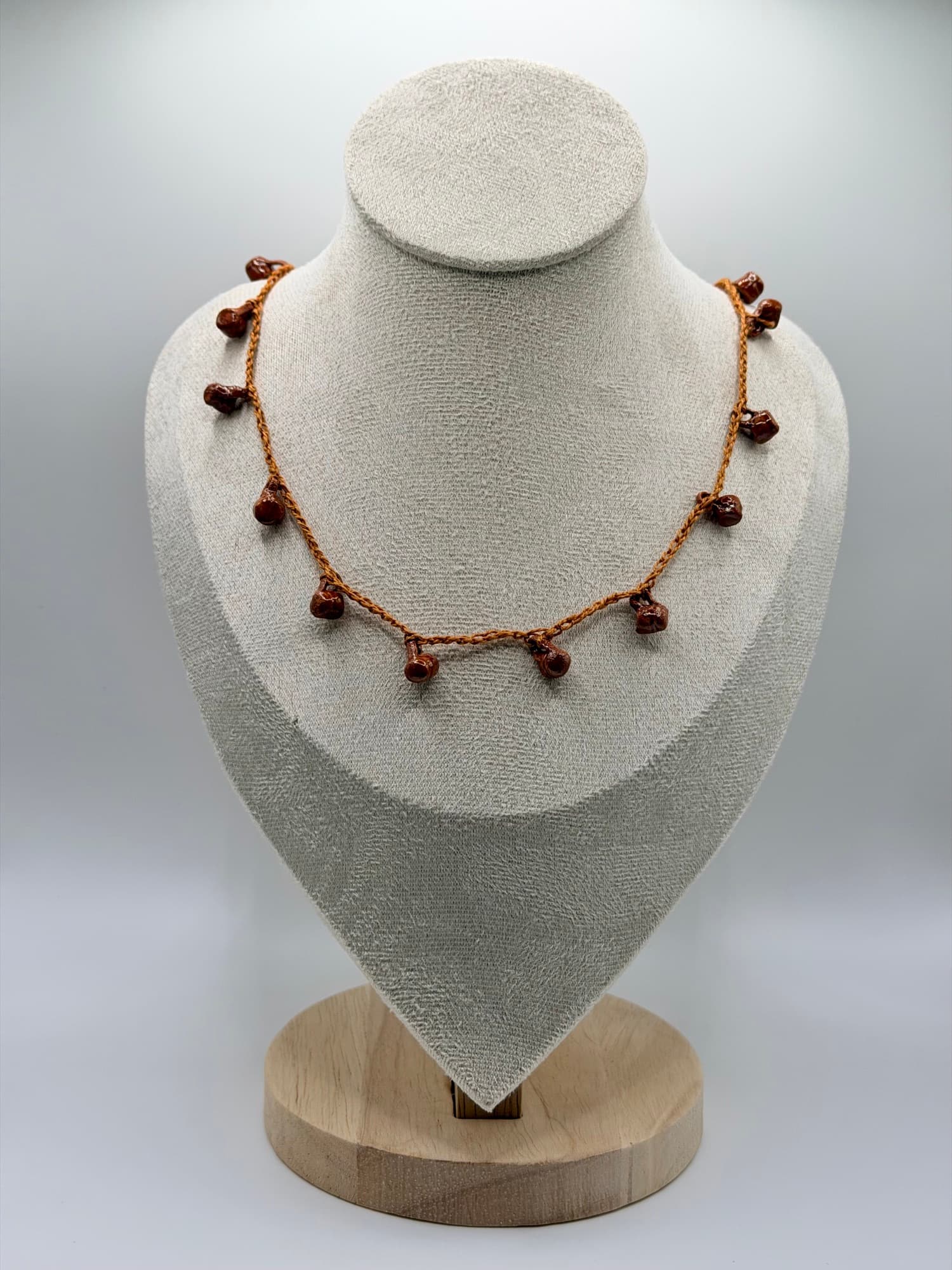 Fiesta de Barro displayed on a linen necklace bust.